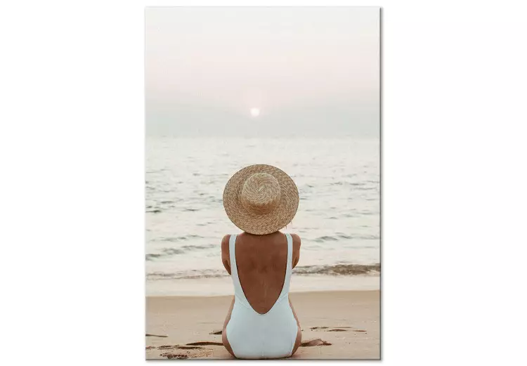Kvinna med hatt på stranden - havslandskap med solnedgång i bakgrunden