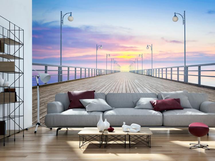Fototapet Solnedgång på piren - landskap med lugnt hav och en vit bro