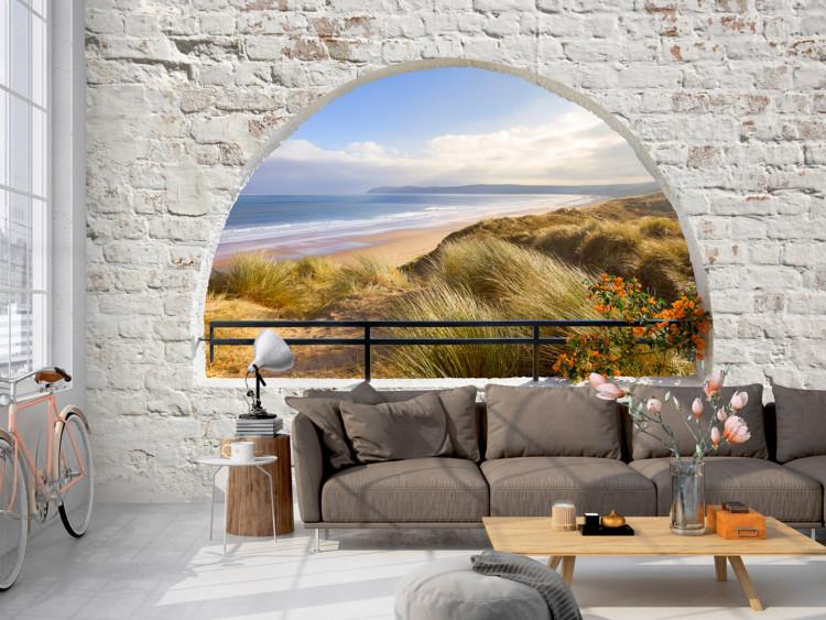 Fototapet Utsikt från fönstret - landskap med hav och sandstrand omgiven av tegelstenar