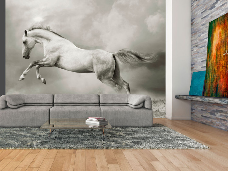 Fototapet Stark hingst - vit hoppande häst på sanden i en grå dimma 61267